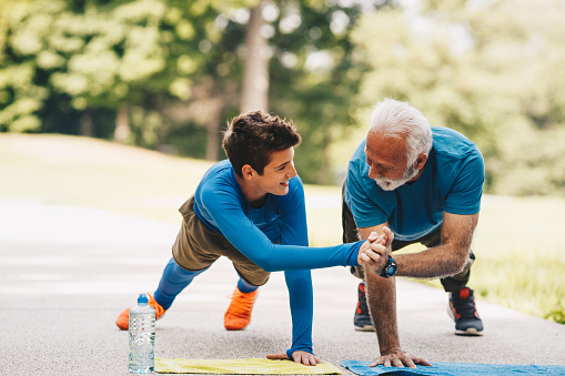 A grandfather and grandson stretching together outdoors
